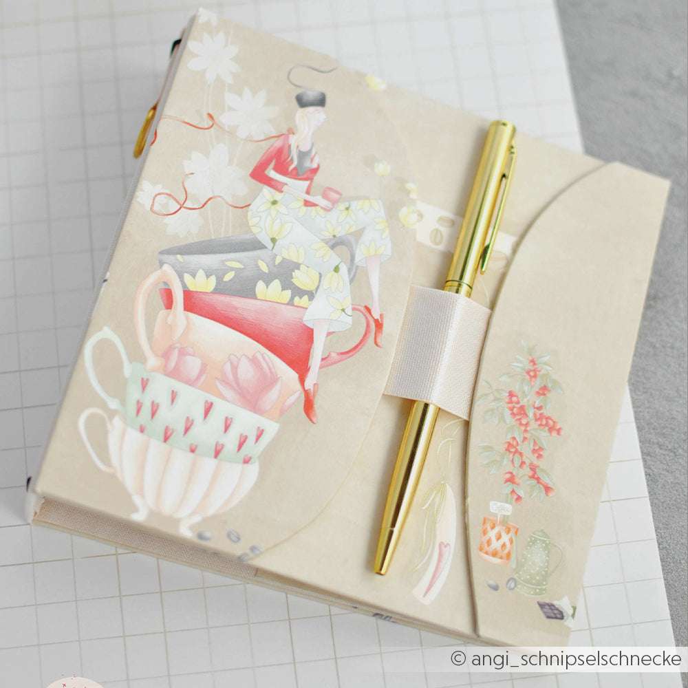 Dieses dekorative Alexandra Renke Notizbuch mit Designpapier, einem goldenen Stift und Teetassen-Illustrationen mit einer Frau auf dem Cover ist ideal für Fans von Papierprojekten oder Buchbinderei.