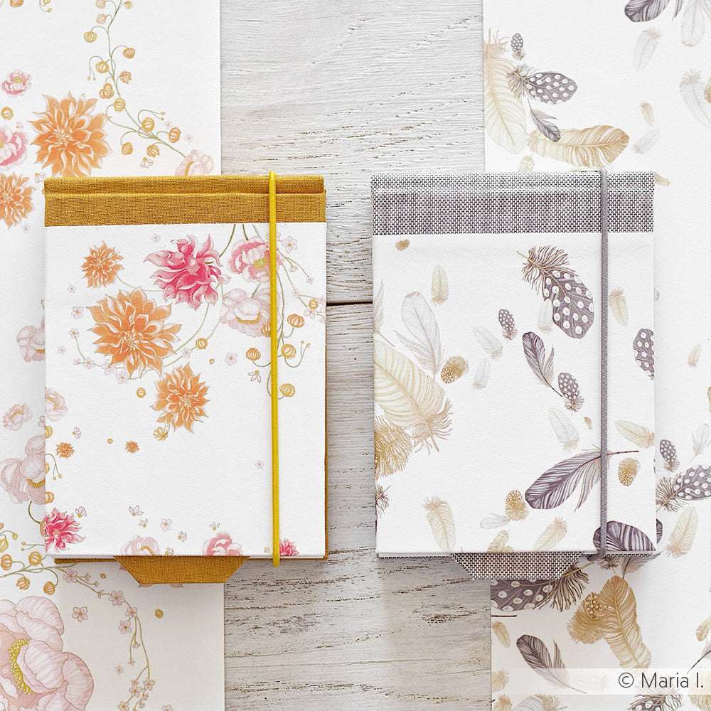 Zwei florale Notizbücher mit Gummibändern von Alexandra Renke liegen auf einer weißen Holzunterlage, umgeben von passendem Pfingstrosen-Dahlien-Designpapier - ideal als Inspiration für Ihr nächstes kreatives Papierprojekt.
