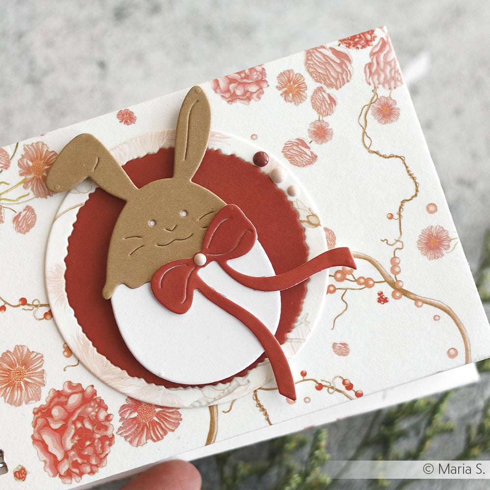 Handgefertigte Grußkarten von Alexandra Renke mit einem Hasengesicht mit roter Schleife auf geblümtem Designpapier, akzentuiert in rosa und rot.