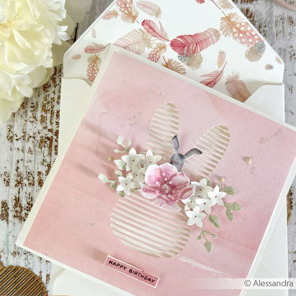 Rosa Geburtstagskarte von Alexandra Renke mit einem Hasenausschnitt, weißen Blumen und einem Umschlag mit Federmotiven - ideal für Papierprojekte oder als charmante Grußkarte aus hochwertigem Designpapier.