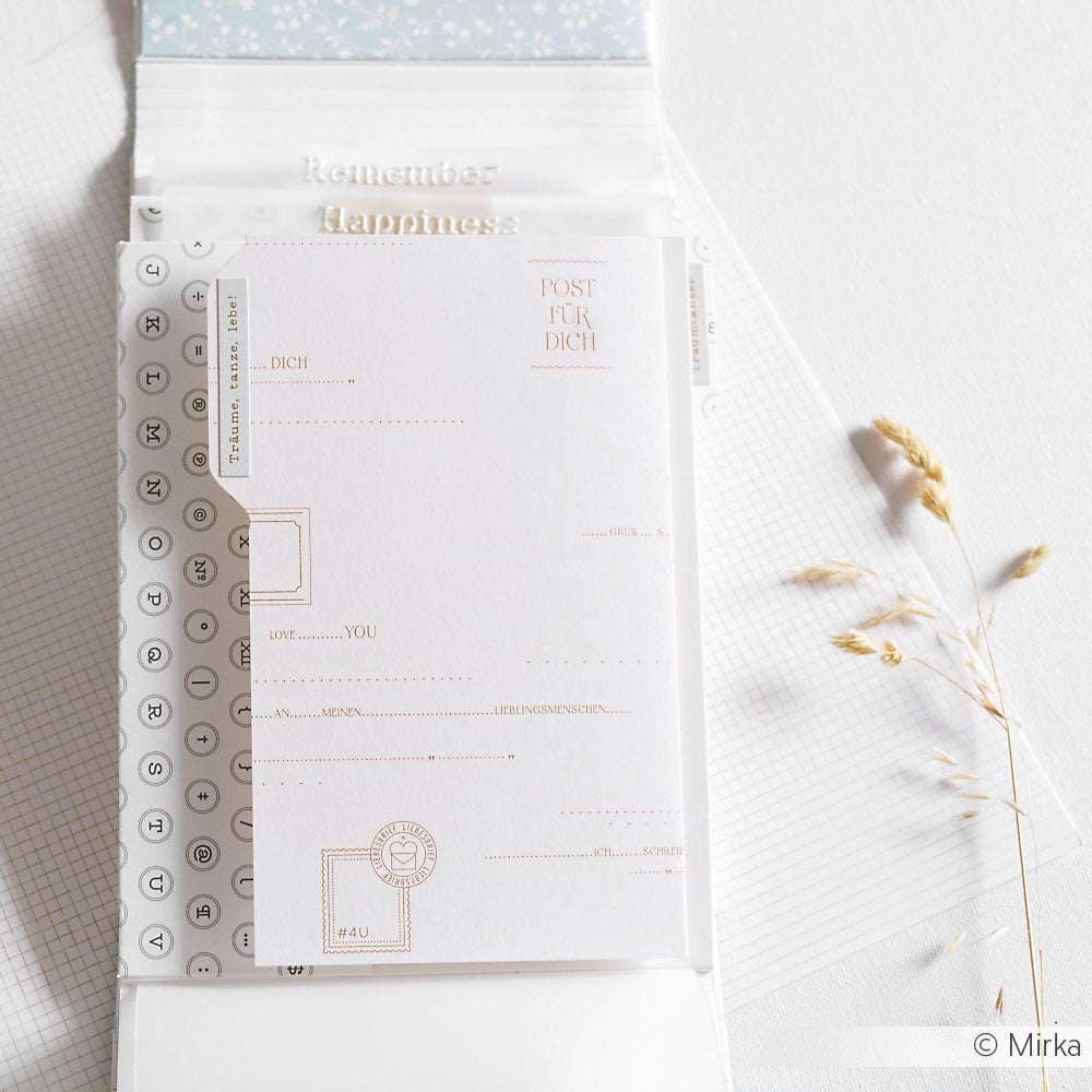 Minimalistisches Briefpapier von Alexandra Renke mit zartem Text- und Designdruck auf hellem Hintergrund mit Akzenten aus getrocknetem Gras.