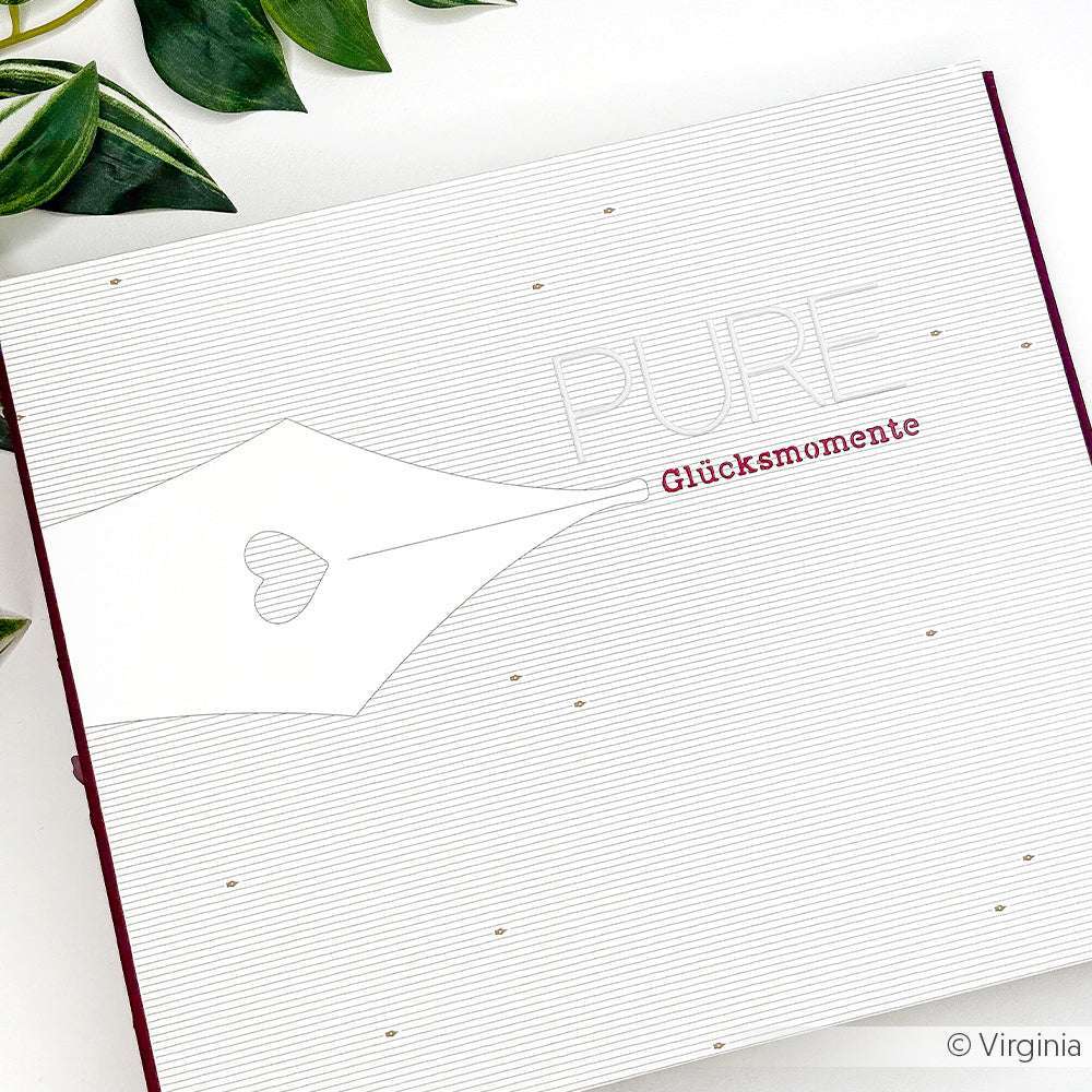 Weiße Karte mit Füllfederhalter und "PURE Glücksmomente" auf gestreiftem Designpapier von Alexandra Renke, akzentuiert durch grüne Blätter - eine stilvolle Wahl für Grußkarten oder kreative Buchbinderei-Projekte.