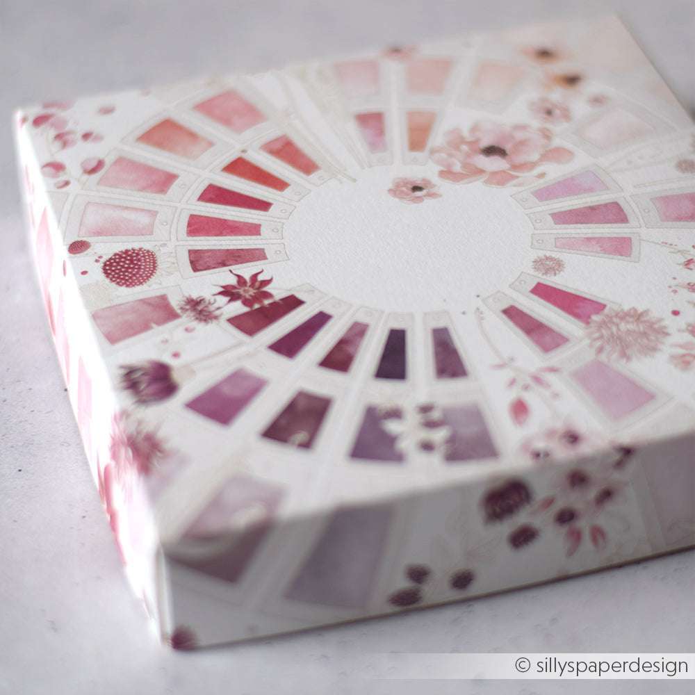 Eine quadratische Schachtel von Alexandra Renke zeigt ein rosa- und lilafarbenes, florales Aquarellmuster, das von Designpapier und dem Farbkartenkreis Beerentöne inspiriert ist, von schräg oben betrachtet.