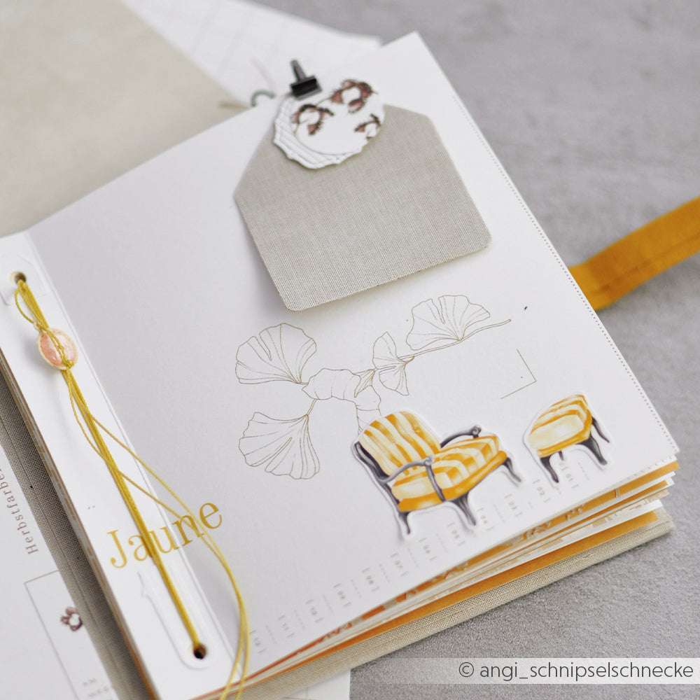 Offenes Scrapbook von Alexandra Renke mit gelben Akzenten, einer Ginkgoblatt-Skizze und Stuhl-Illustrationen - eine perfekte Inspiration für Papierprojekte oder die Gestaltung einzigartiger Grußkarten mit dem Designpapier Ihrer Wahl.