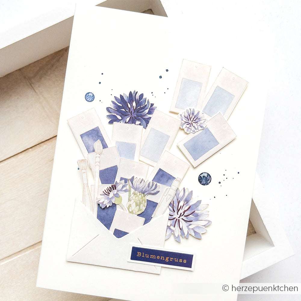 Eine handgefertigte Karte von Alexandra Renke mit lila Blumen, Farbklecksen, Pinseln und "Blumengruß" auf weißem Grund - ideal für Papierprojekte oder zur Kombination mit Ihrem Lieblingsdesignpapier.