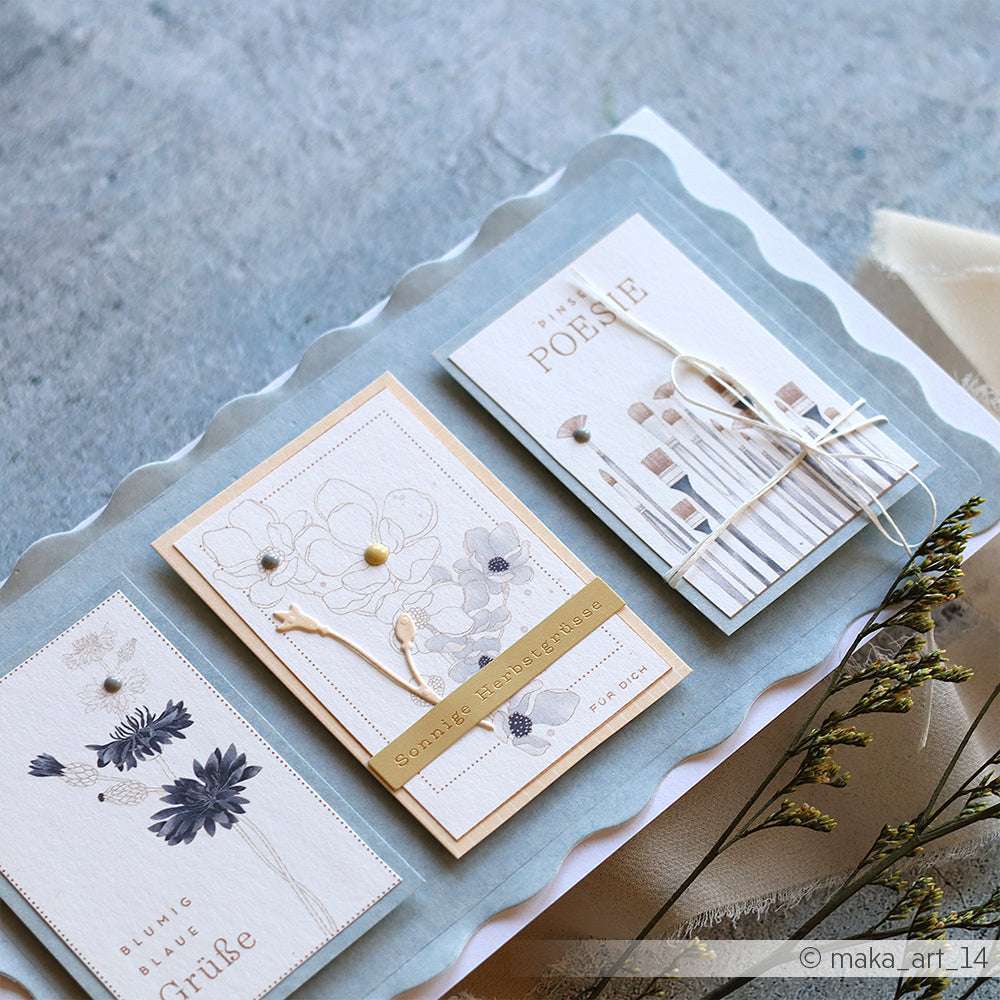Drei handgefertigte, florale Grußkarten von Alexandra Renke mit zarten Trockenblumen und pastellfarbenem Designpapier auf einer gewellten Oberfläche - ein charmantes Schaufenster für Ihre Papierprojekte.