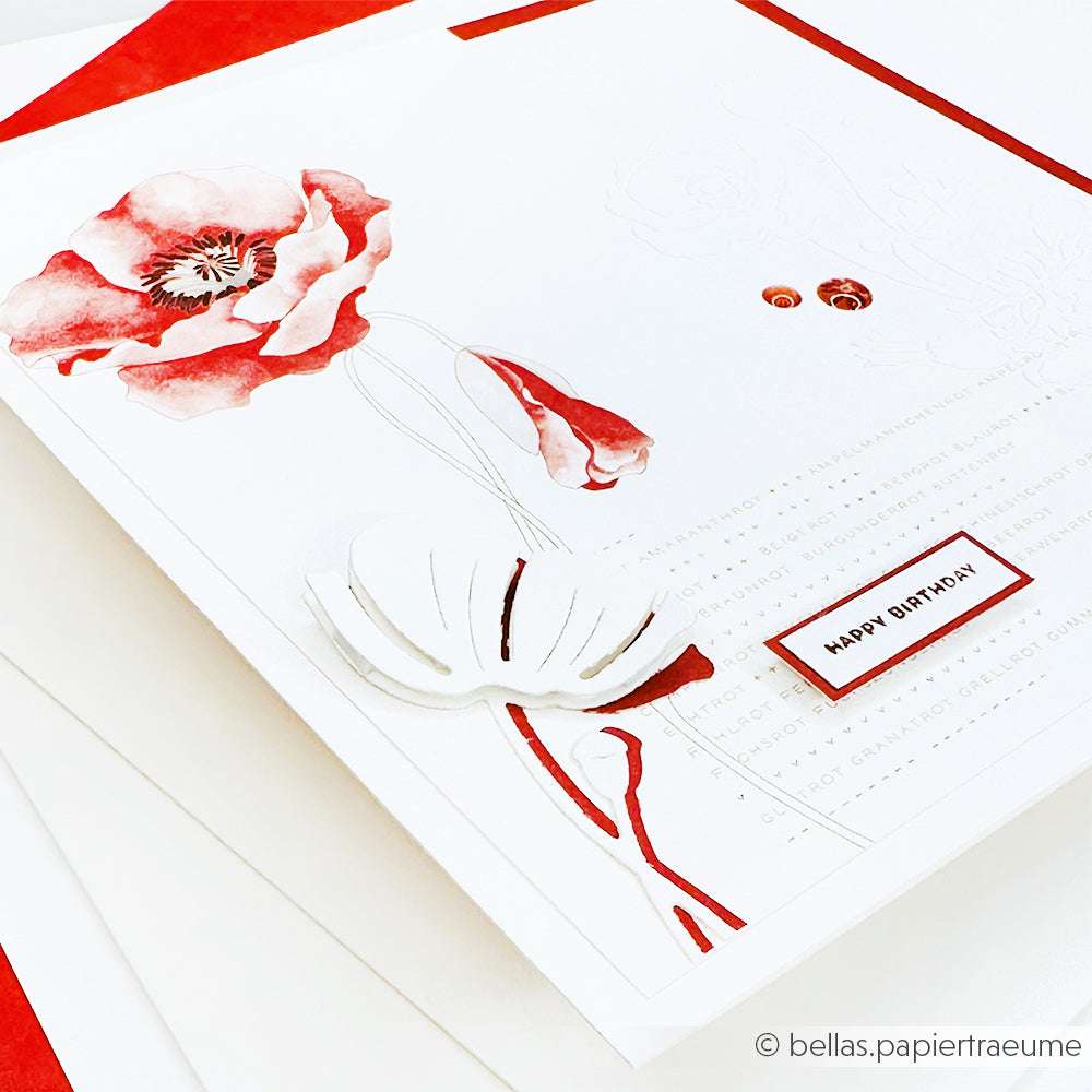 Eine Geburtstagskarte von Alexandra Renke mit roten und weißen Mohnblumen auf Designpapier, mit einem "Happy Birthday"-Aufkleber auf weißem Hintergrund - ideal für Grußkarten oder Papierprojekte.