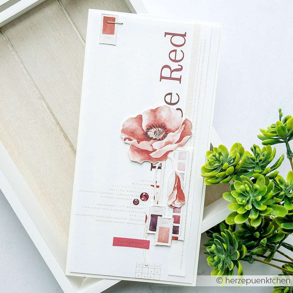 Eine handgefertigte Karte von Alexandra Renke mit kreativen Blumenmustern, roter Mohnillustration und Text, rot akzentuiert und wunderschön neben einer grünen Sukkulentenpflanze präsentiert.