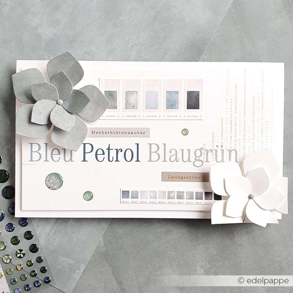 Eine Karte mit Farbmustern, Text und zwei Papierblumen, die mit dem Designpapier Kreative Blütenpracht von Alexandra Renke auf einem grauen Hintergrund gestaltet wurden - ideal für inspirierende Papierprojekte.