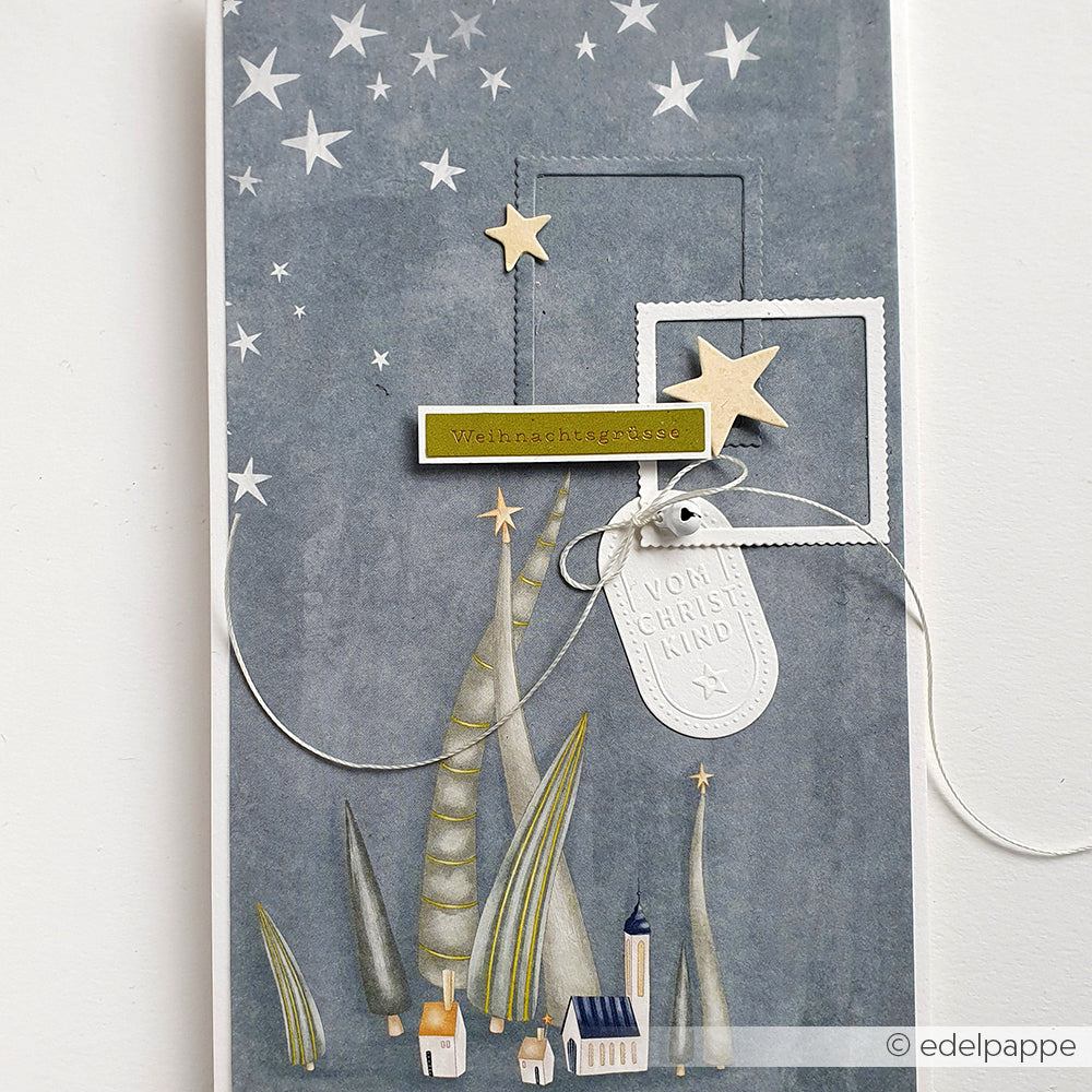 Handgefertigte Weihnachtskarte von Alexandra Renke, hergestellt mit Bastelpapier und verziert mit Sternen, Bäumen, kleinen Häusern und deutschen Weihnachtsgrüßen auf grauem Hintergrund.