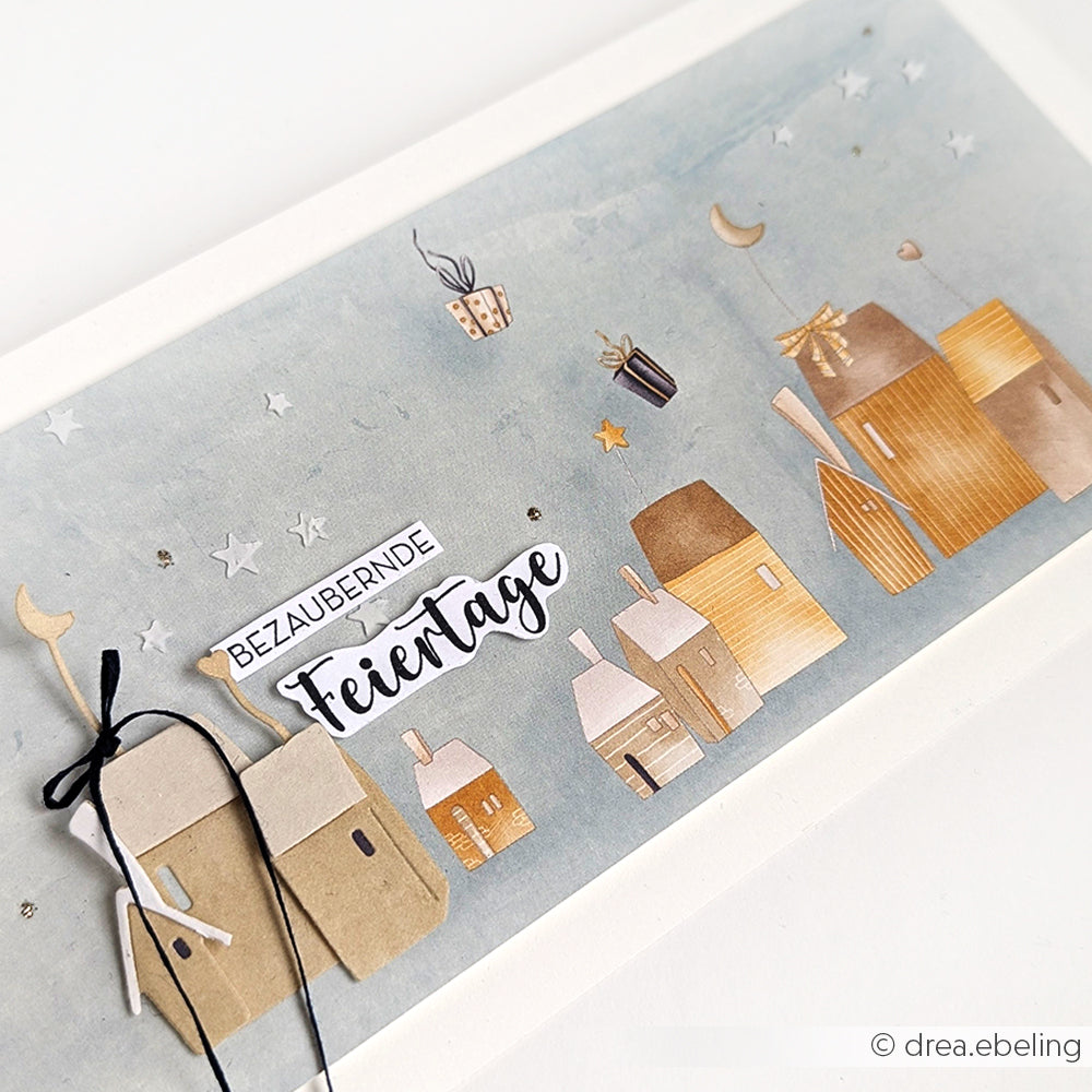 Handgefertigte Weihnachtskarte von Alexandra Renke mit ausgeschnittenen Häusern, Sternen, Mond und "Bezaubernde Feiertage" auf blauem Designpapier Weihnachten-perfekt für festliche Papierprojekte oder in Verbindung mit Weihnachts Figurinen.