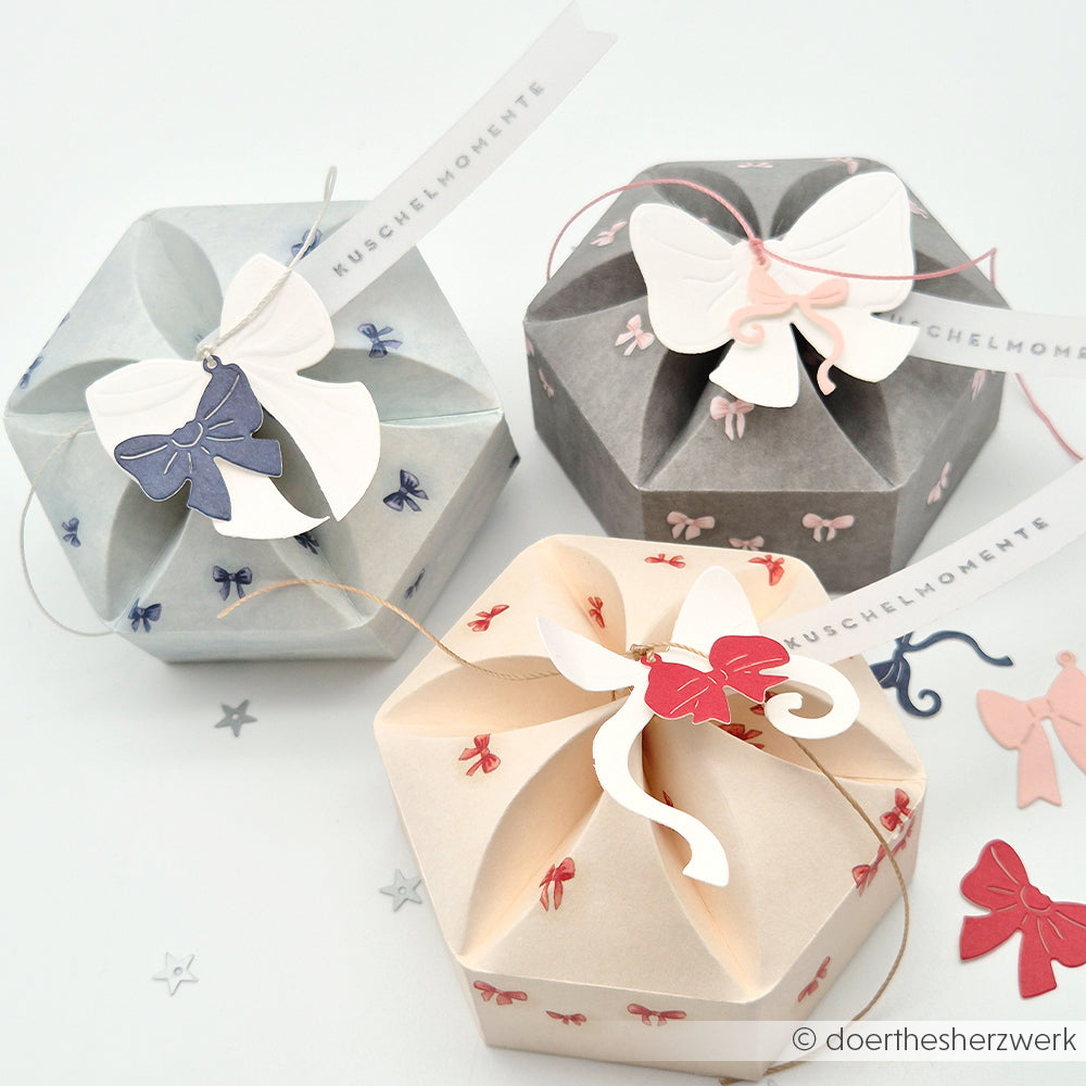 Drei sechseckige Geschenkboxen von Alexandra Renke in Grau, Weiß und Creme mit Schleifen, Schmetterlingsanhängern und eleganten Akzenten aus Himmelblau Designpapier - perfekt für Papierprojekte.