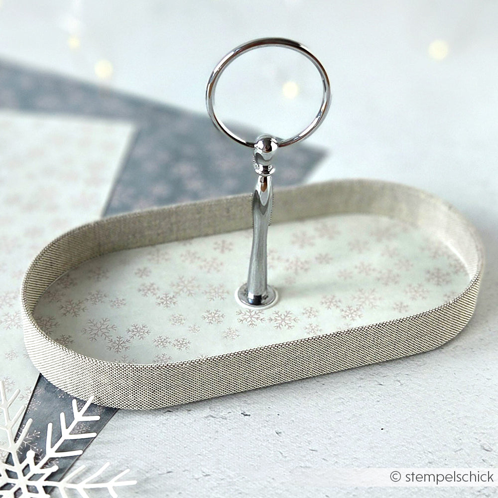 Ovales Tablett von Alexandra Renke mit silbernem Henkel, Schneeflockenmuster und metallischem Rand - ideal, um Grußkarten oder Papierprojekte aus Designpapier Schneeflockenzauber Jaspisgrün vor einer winterlichen Kulisse zu präsentieren.