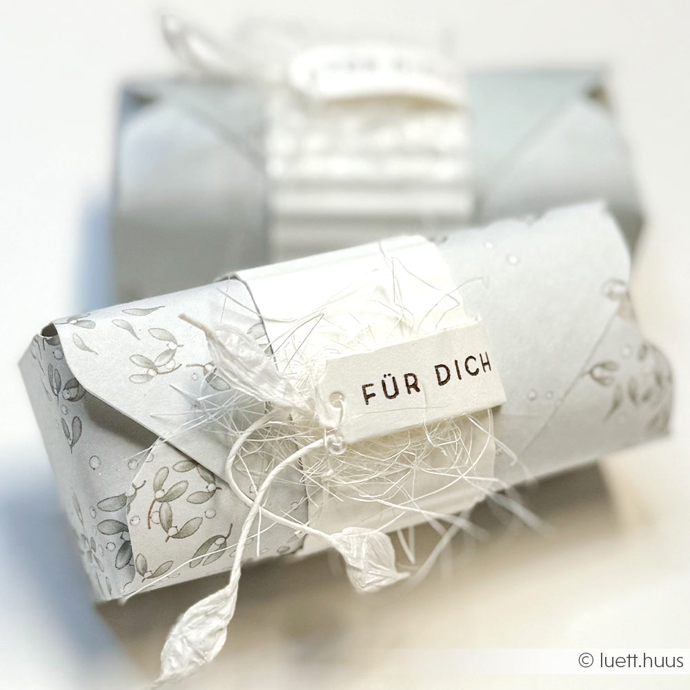 Geschenkverpackung aus weißem Designpapier von Alexandra Renke mit "FÜR DICH"-Anhänger, Kordel und zarten Mistelwirbel-Jaspisgrün-Details - perfekt für Ihre Papierprojekte.