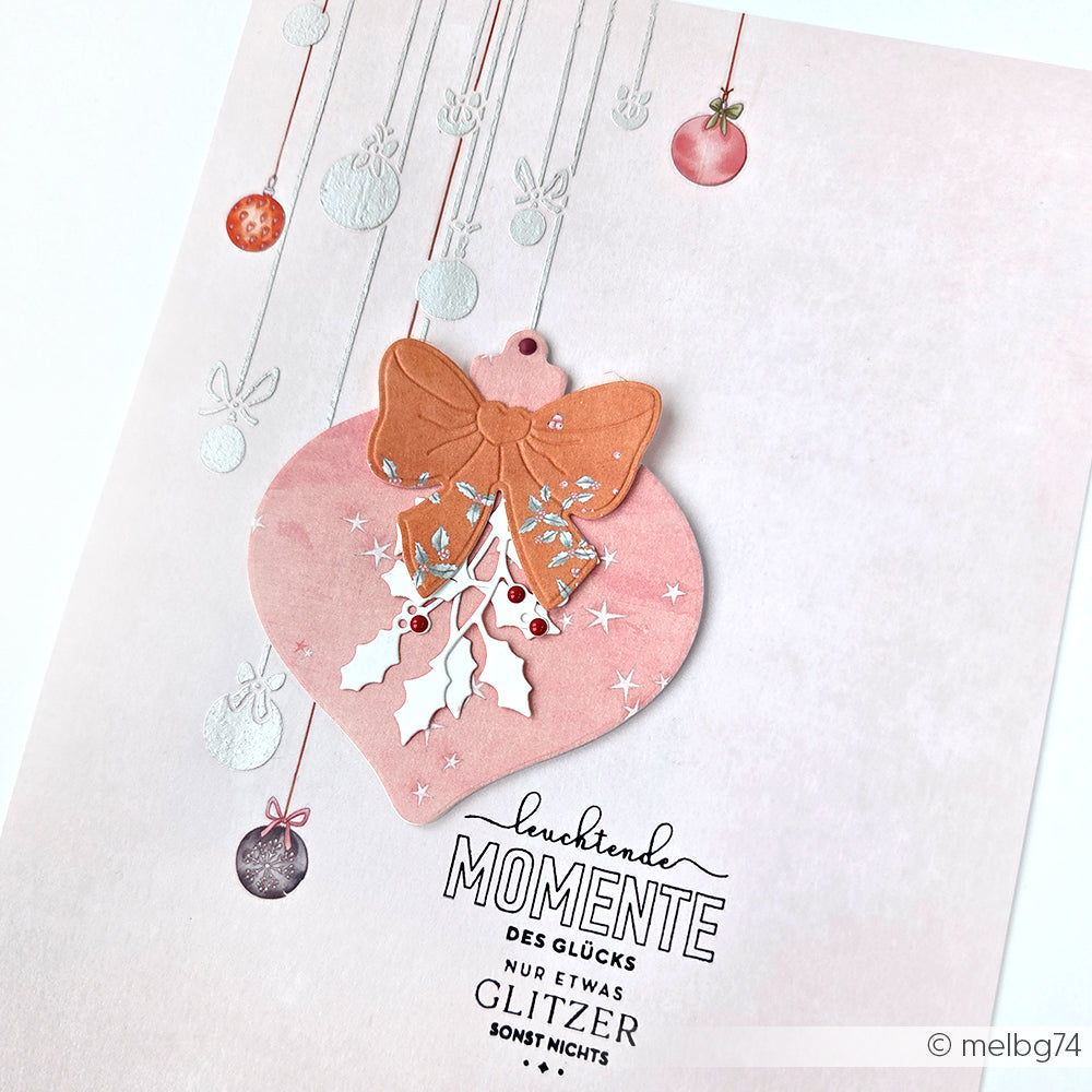 Rosa Weihnachtskarte mit großem Ornament, Schleife, Stechpalme und kleineren hängenden Ornamenten mit deutschem Text. Mit Alexandra Renke Designpapier aus der Sternenzauber Apricot Kollektion für einen festlichen Look.