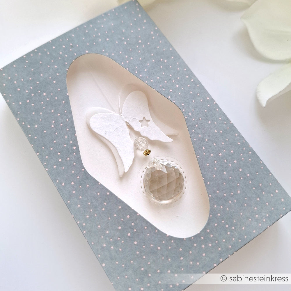 Geschenkkarte mit Alexandra Renke Designpapier: ein weißer Engel und ein Kristallanhänger auf blauem Hintergrund mit kleinen weißen Punkten.
