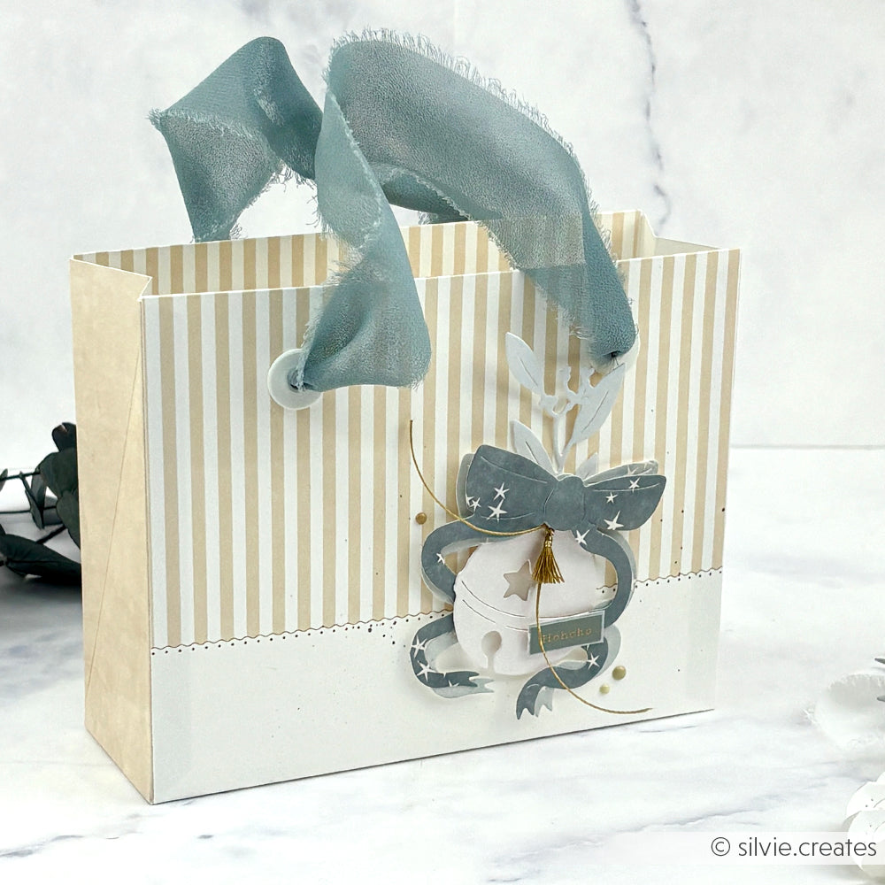 Creme- und goldgestreifte Geschenktasche von Alexandra Renke mit blauem Band und Schleife auf weißem Untergrund - ideal zum Überreichen von Grußkarten oder zum Kombinieren mit elegantem Designpapier.