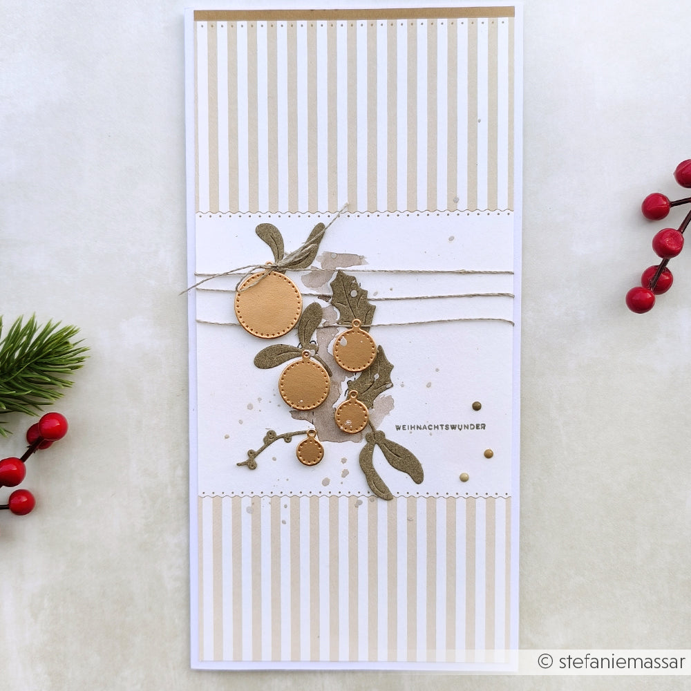 Handgemachte Weihnachtskarte von Alexandra Renke mit goldenen Ornamenten, grünen Blättern, einem gestreiften Designpapier-Hintergrund und Akzenten aus Ranken und Beeren.