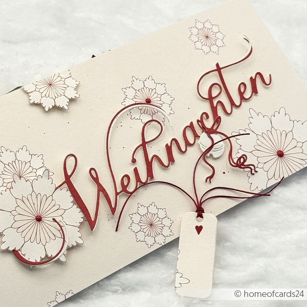 Cremefarbene Karte von Alexandra Renke mit "Weihnachten" in roter Schrift, floralem Designpapier und einem kleinen Anhänger mit rotem Herz an einer Schnur - ideal für Papierprojekte oder Buchbinderei.