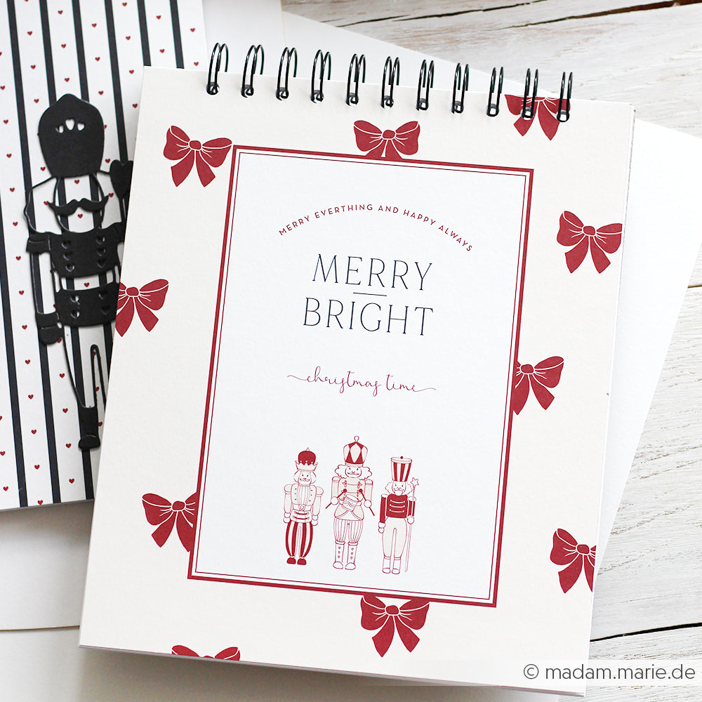 Spiral-Notizbuch von Alexandra Renke mit einem fröhlichen Einband mit roten Schleifen und Nussknacker-Illustrationen auf Weiß - ideal für Papierprojekte oder alle, die einzigartige Buchbinderei-Designs lieben.