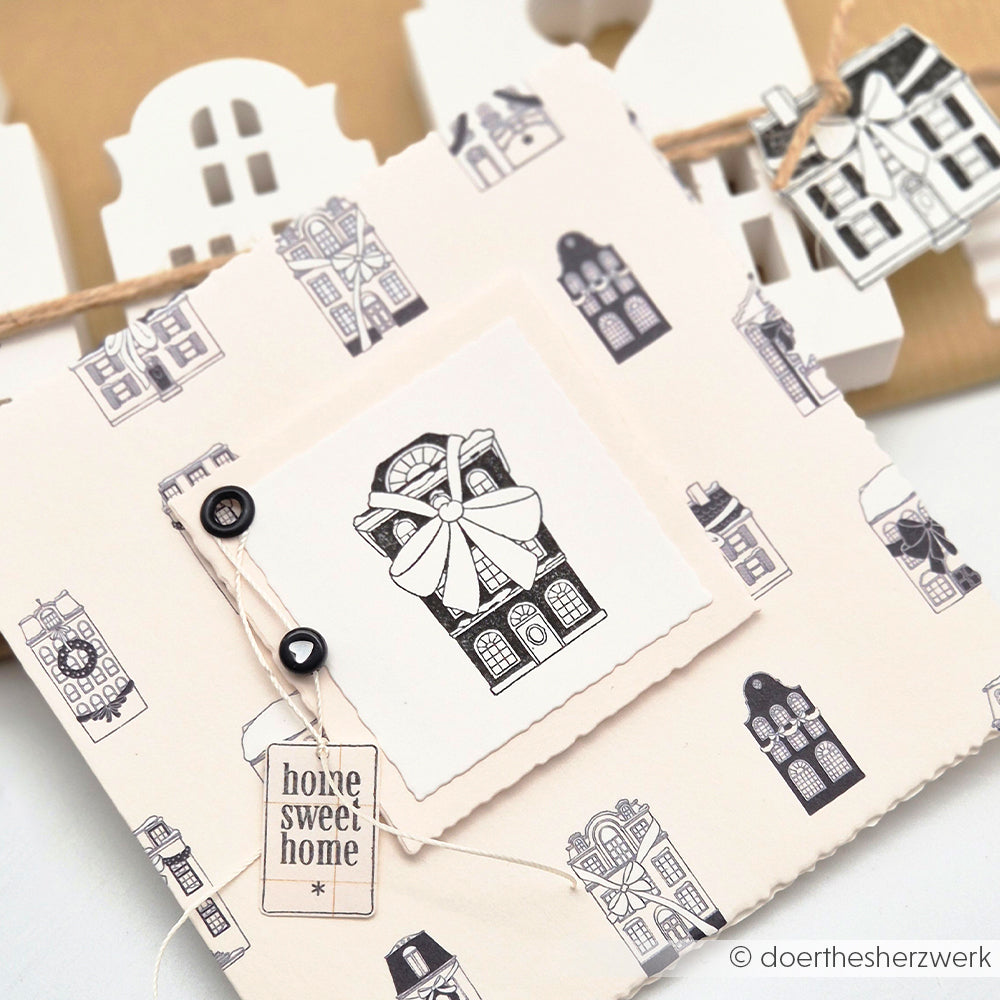 Eine handgefertigte Grußkarte von Alexandra Renke mit Haus-Illustrationen, Buttons und einem "Home Sweet Home"-Tag auf neutralem Hintergrund - ideal für Papierprojekte oder alle, die einzigartiges Designpapier lieben.