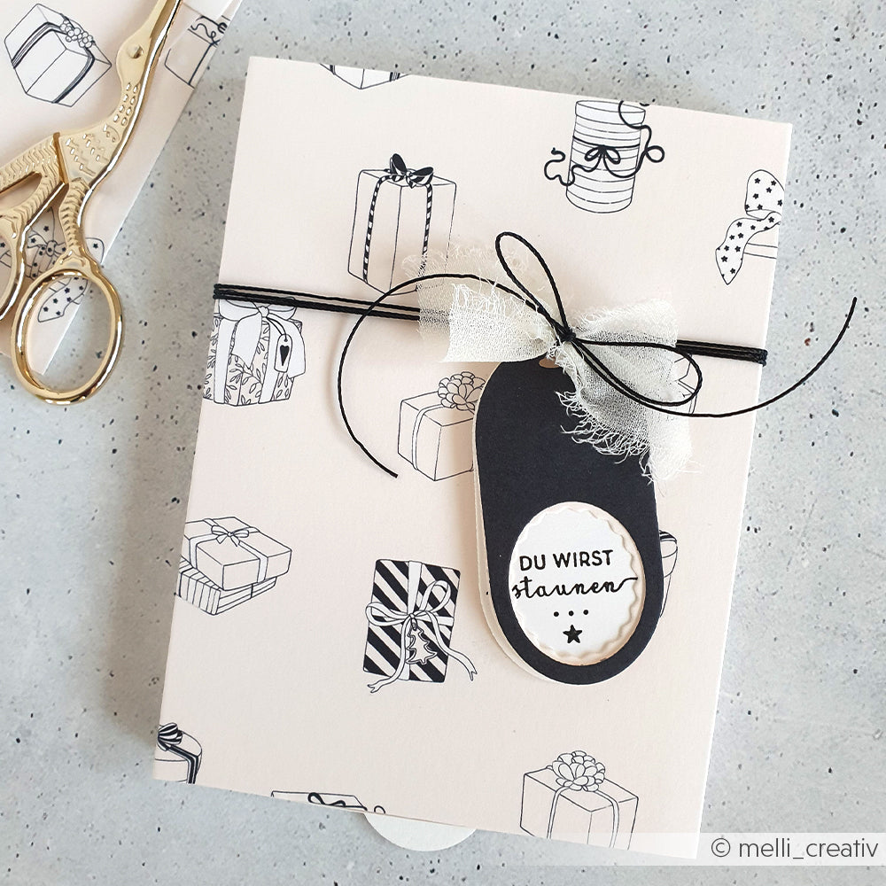 Geschenkverpackte Karte von Alexandra Renke mit schwarzen und weißen Geschenken, schwarzem Band und einem "Du wirst staunen"-Anhänger - ideal für Papierprojekte oder in Verbindung mit einzigartigem Designpapier.