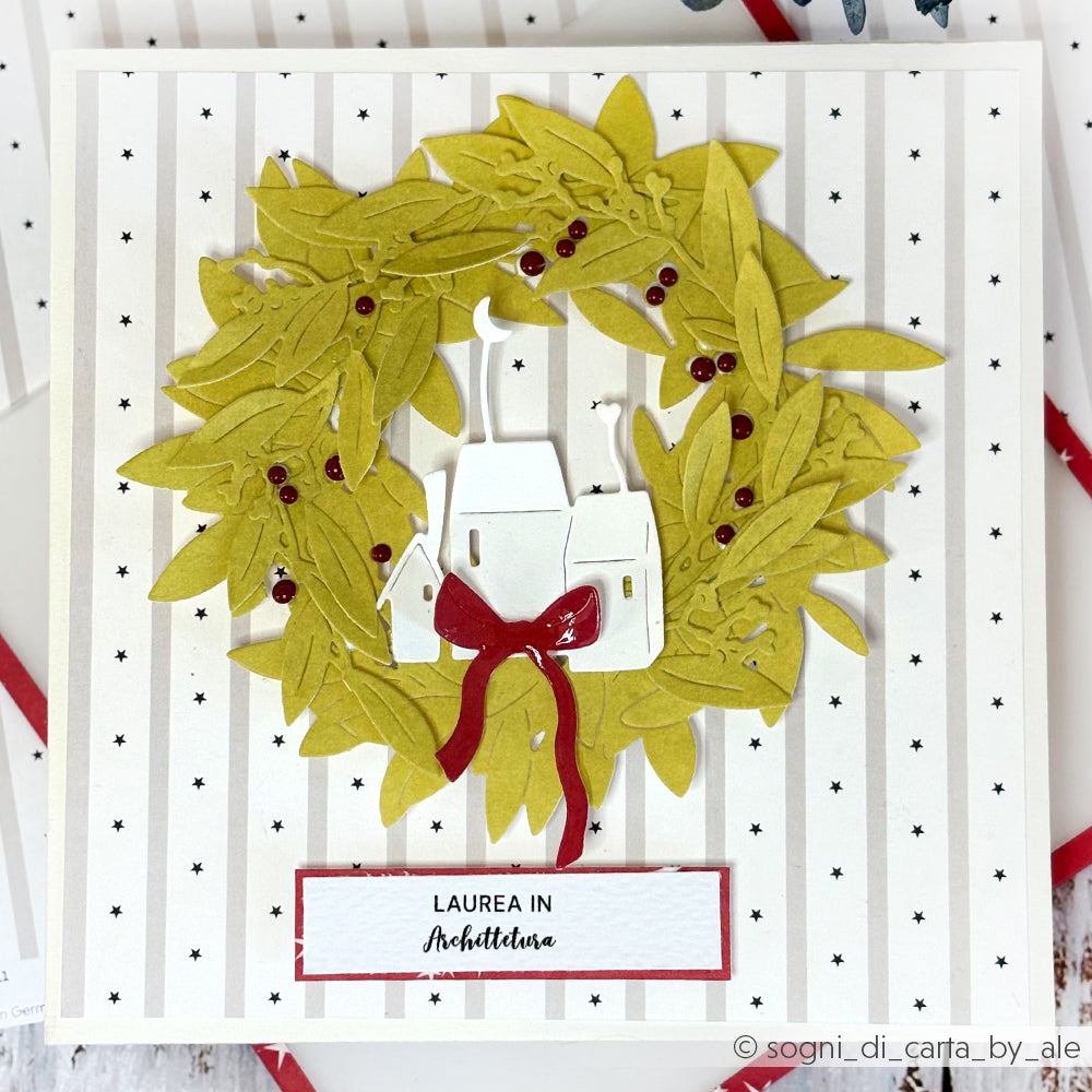 Die handgefertigte Karte von Alexandra Renke zeigt einen grünen Lorbeerkranz, rote Akzente und eine italienische Abschlussbotschaft auf einem gestreiften Hintergrund in Sternenstreifen Grau - perfekt für einzigartige Papierprojekte oder als besondere Buchbinderei.