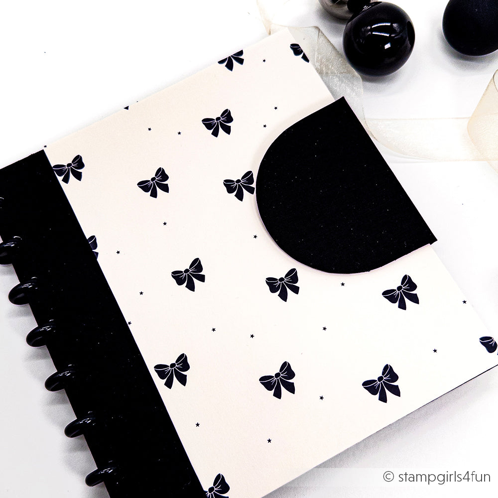 Ein schicker Planer von Alexandra Renke mit einem Designpapier Schleifenregen Samtschwarz mit schwarzen und weißen Schleifen, schwarzen Scheiben und dekorativen Kugeln - ideal für stilvolle Buchbinderei oder kreative Papierprojekte.