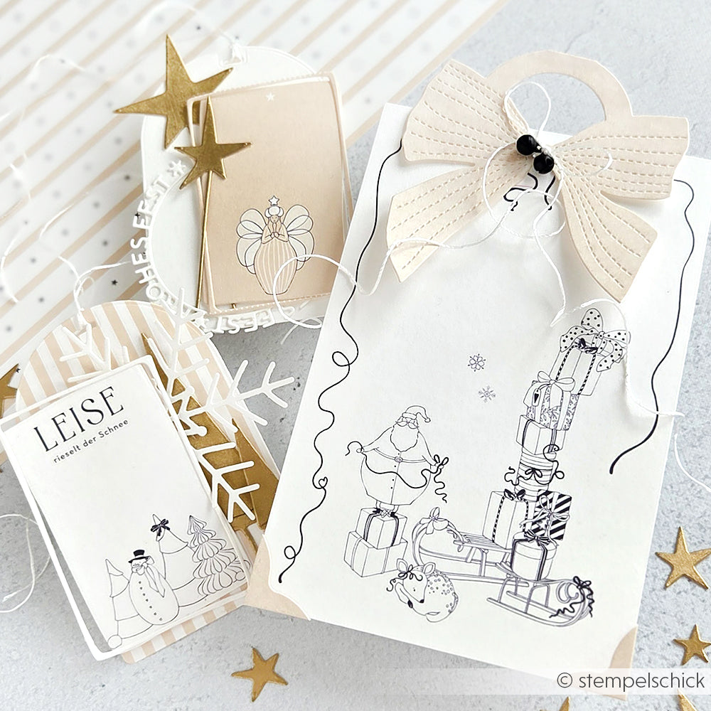 Alexandra Renke Geschenktüten und -anhänger mit handgezeichneten Weihnachtsmotiven, eine große Schleife, festliche Dekoration und Designpapier-Akzente sind wunderschön auf dem Tisch arrangiert.