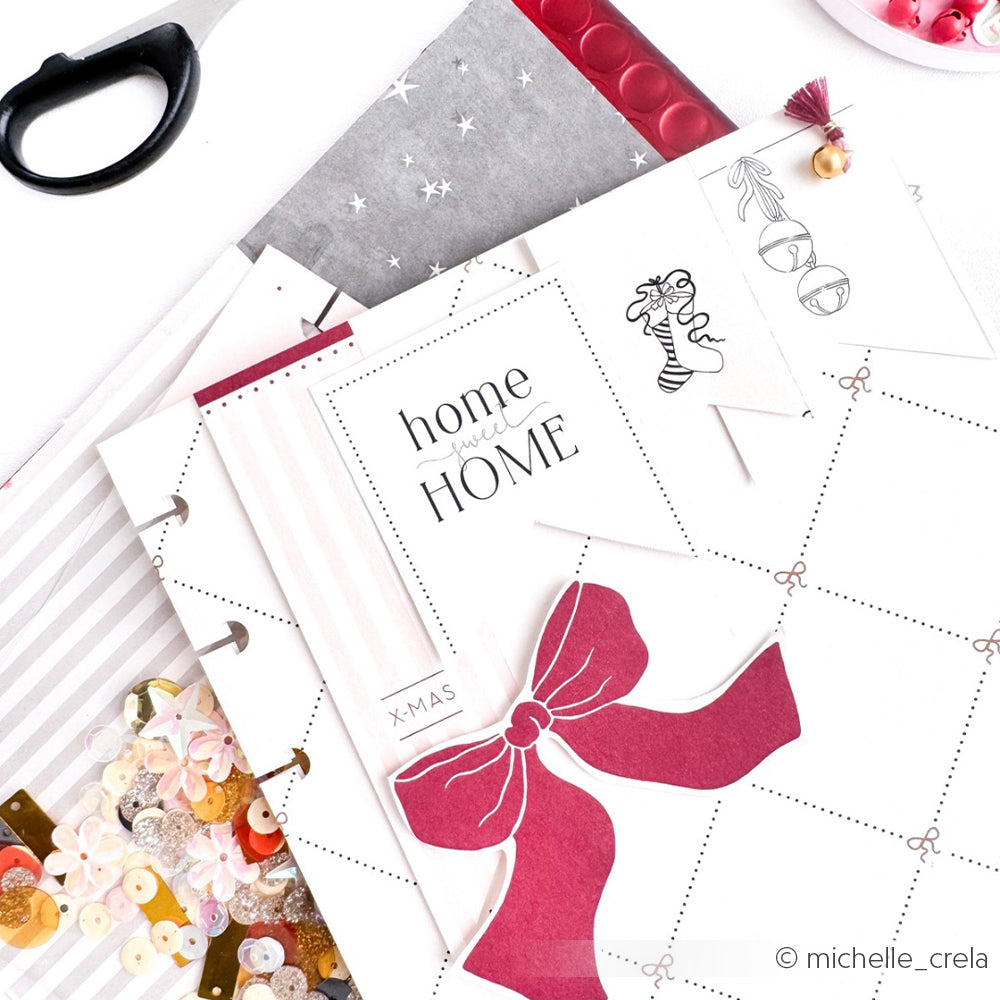 Alexandra Renke Scrapbooking-Zubehör - rosa Schleife, Pailletten, Schere und "Home Sweet HOME"-Papier auf einem weißen Tisch - ideal für Papierprojekte mit dem Kärtchenbogen Liebe im Gepäck oder Ihrem Lieblingsdesignpapier.