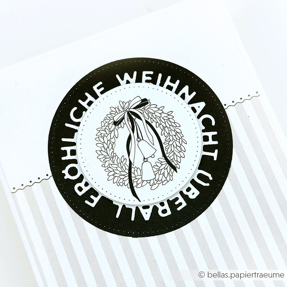 Schwarz-weiße Karte von Alexandra Renke mit einem Kranz und dem Text "Fröhliche Weihnacht überall". Ideal für Papierprojekte oder Buchbinderei, bringt sie festlichen Charme in Ihr Weihnachtsbasteln.