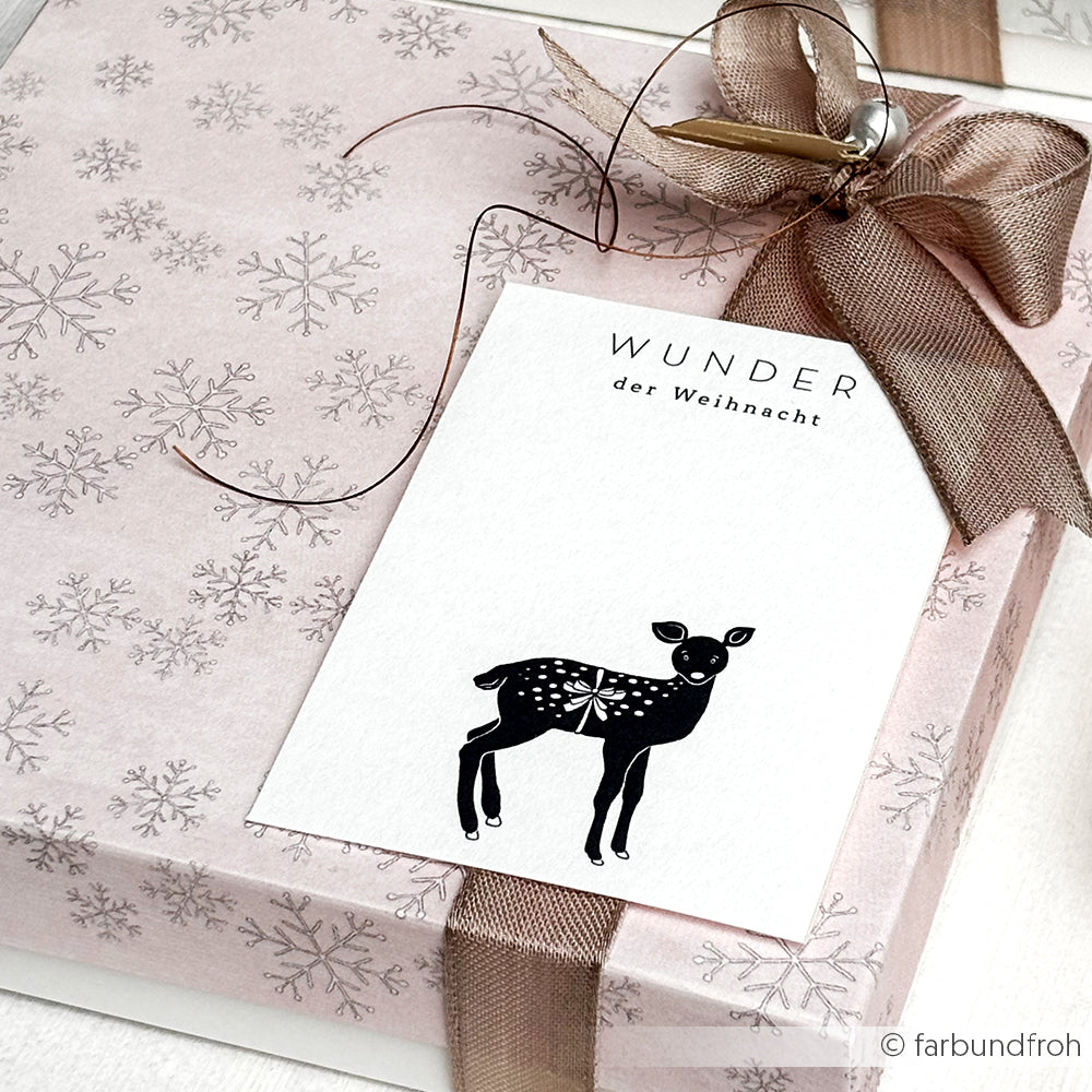 Weihnachtsmagie in zartrosa Schneeflocke von Alexandra Renke Designpapier mit brauner Schleife und einer Papierprojekte Grußkarte mit schwarzem Hirschmotiv.