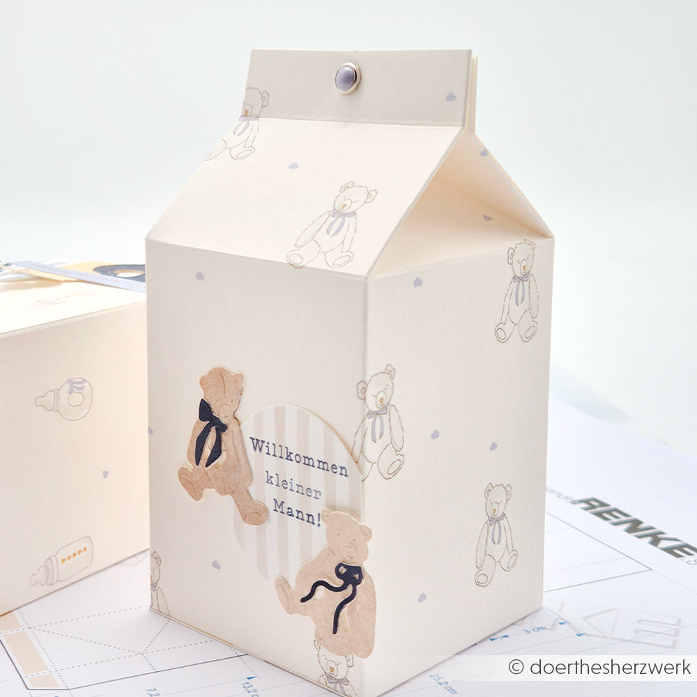 Cremefarbene Geschenkbox in Form einer Milchtüte mit Teddybären und deutschem Text aus dem Designpapier Erster Teddy blau von Alexandra Renke - ideal für Papierarbeiten oder Buchbinderei-Projekte.