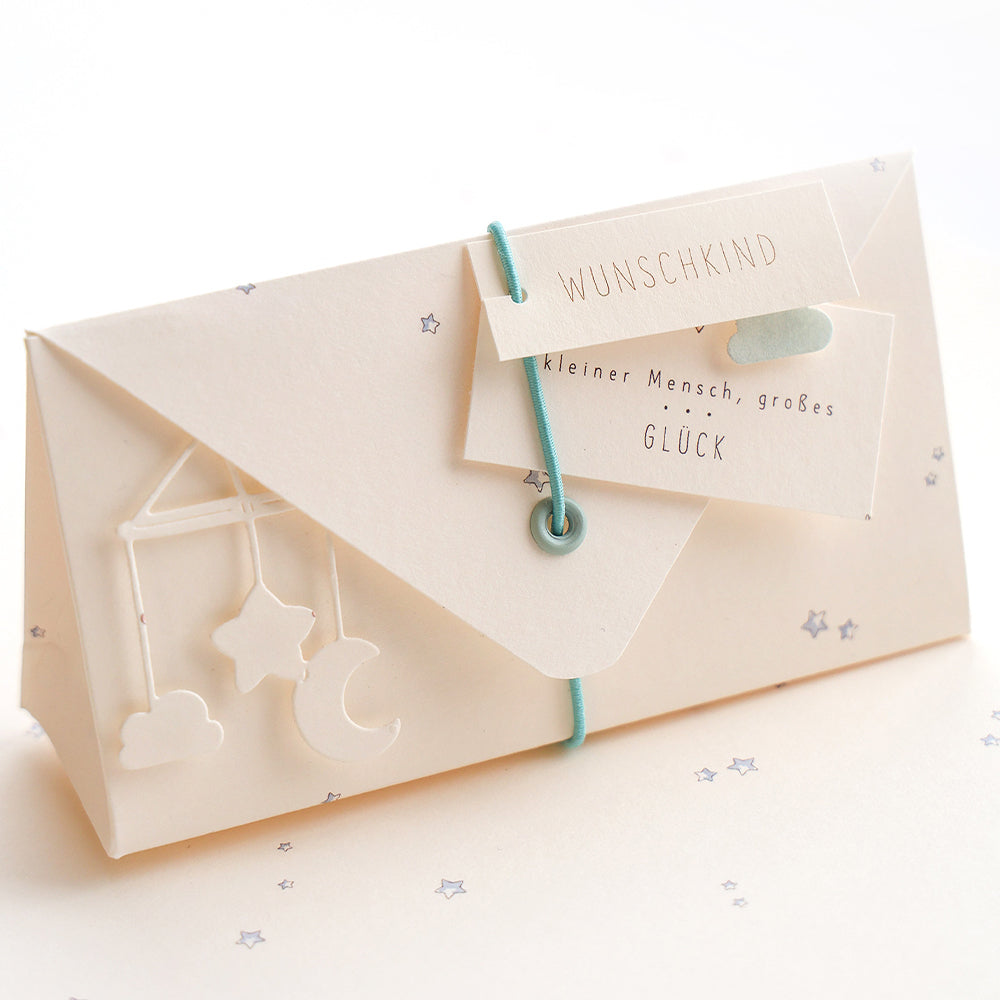 Cremefarbener Umschlag mit tealfarbener Kordel, Sternen- und Monddekor und einer WUNSCHKIND-Karte - perfekt für Projekte oder einzigartige Grußkarten. Mit Alexandra Renke Designpapier Sternenhimmel hellblau für einen verträumten Touch.