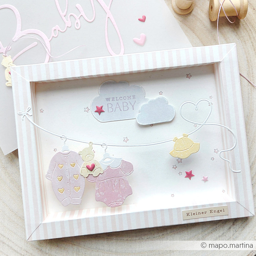 Schattenbox-Karte mit Babykleidung, Teddybär und Wolken, mit Alexandra Renke Designpapier Sternenhimmel hellrosa und pastellrosa Akzenten. Ideal für Papierprojekte oder Buchbinderei als charmantes Welcome Baby Andenken.