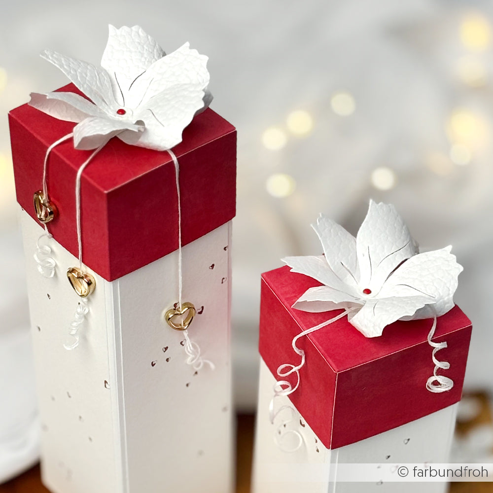 Zwei hohe Geschenkschachteln von Alexandra Renke mit rotem Deckel, weißem Blumendekor und goldenen Herzanhängern an gewellten Schnüren - perfekt für Papierprojekte oder Buchbinderei, gefertigt mit Designpapier Herzchen rot für ein charmantes Finish.