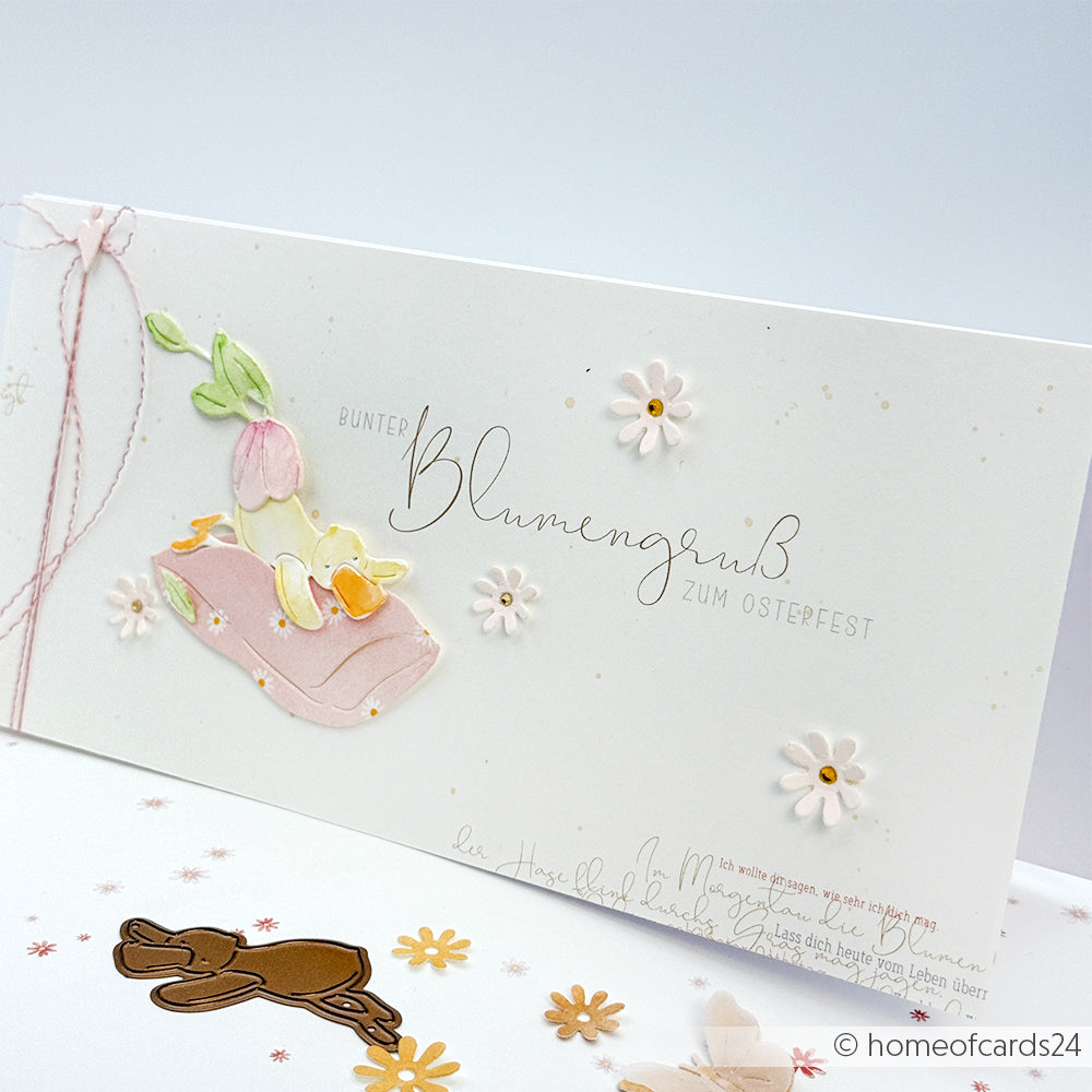 Handgefertigte Osterkarte von Alexandra Renke aus Designpapier mit Blumen- und Hasendekoration, Pastellfarben und deutschem Text auf strahlend weißem Hintergrund.