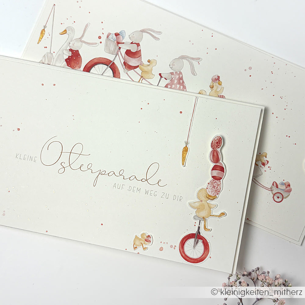 Charmante Postkarte von Alexandra Renke mit illustrierten Hasen - einer jongliert Eier auf einem Einrad, andere fahren Rad - und deutschem Text. Ideal für die Gestaltung von Papier zum Thema Osterparade oder für Papierprojekte in Ihrer Buchbinderei.