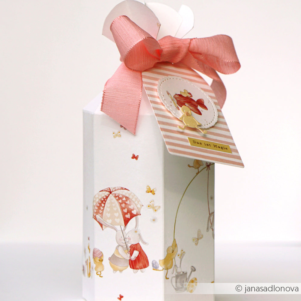Dekorative Geschenkschachtel von Alexandra Renke mit Tierillustrationen, rosafarbenem Band und einem Kronenanhänger mit deutschem Text - hergestellt mit Buchbinderei-Techniken und dem entzückenden Designpapier Osterglück.