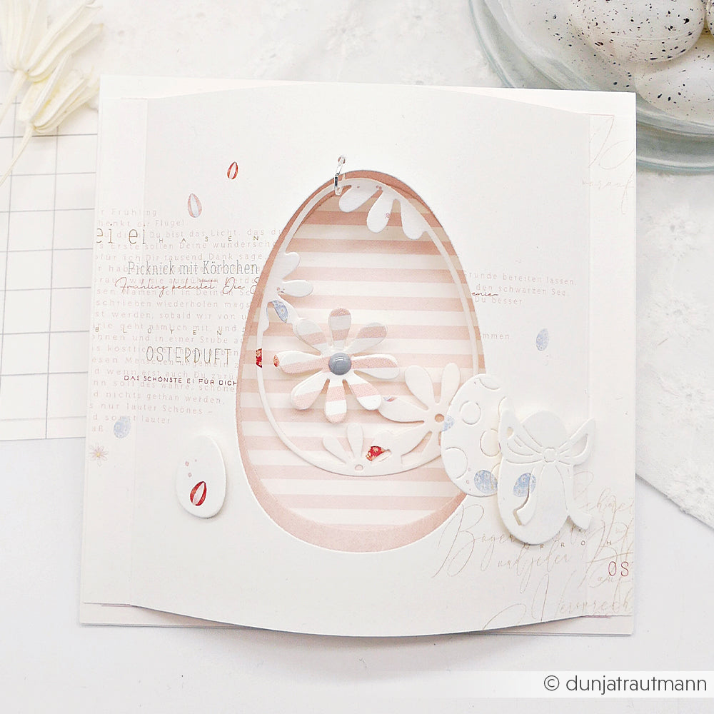 Handgefertigte Osterkarte von Alexandra Renke mit ausgeschnittenem Ei, floralem Muster und pastellfarbenen Streifen auf hochwertigem Designpapier - ideal für Papierprojekte oder als liebevolles Geschenk.