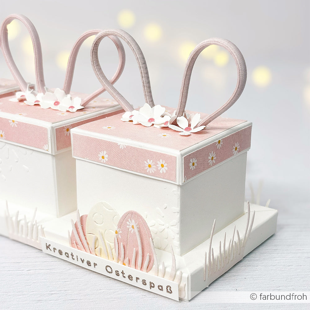 Zwei pastellrosa und weiße Geschenkboxen von Alexandra Renke, hergestellt mit Designpapier und verziert mit Hasenohren, Blumen, Margeritenreigen auf Rosa und Ostereierausschnitten - ideal für charmante Papierarbeiten.