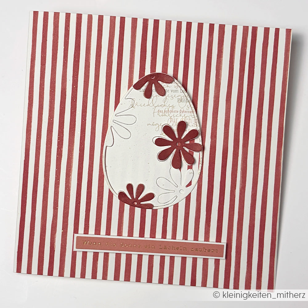 Quadratische Karte aus dem Designpapier Streifen Rot von Alexandra Renke mit roten und weißen Längsstreifen, einem Eierausschnitt und roten Blüten in der Mitte - ideal für kreative Papierprojekte und Designpapiere Basteln.