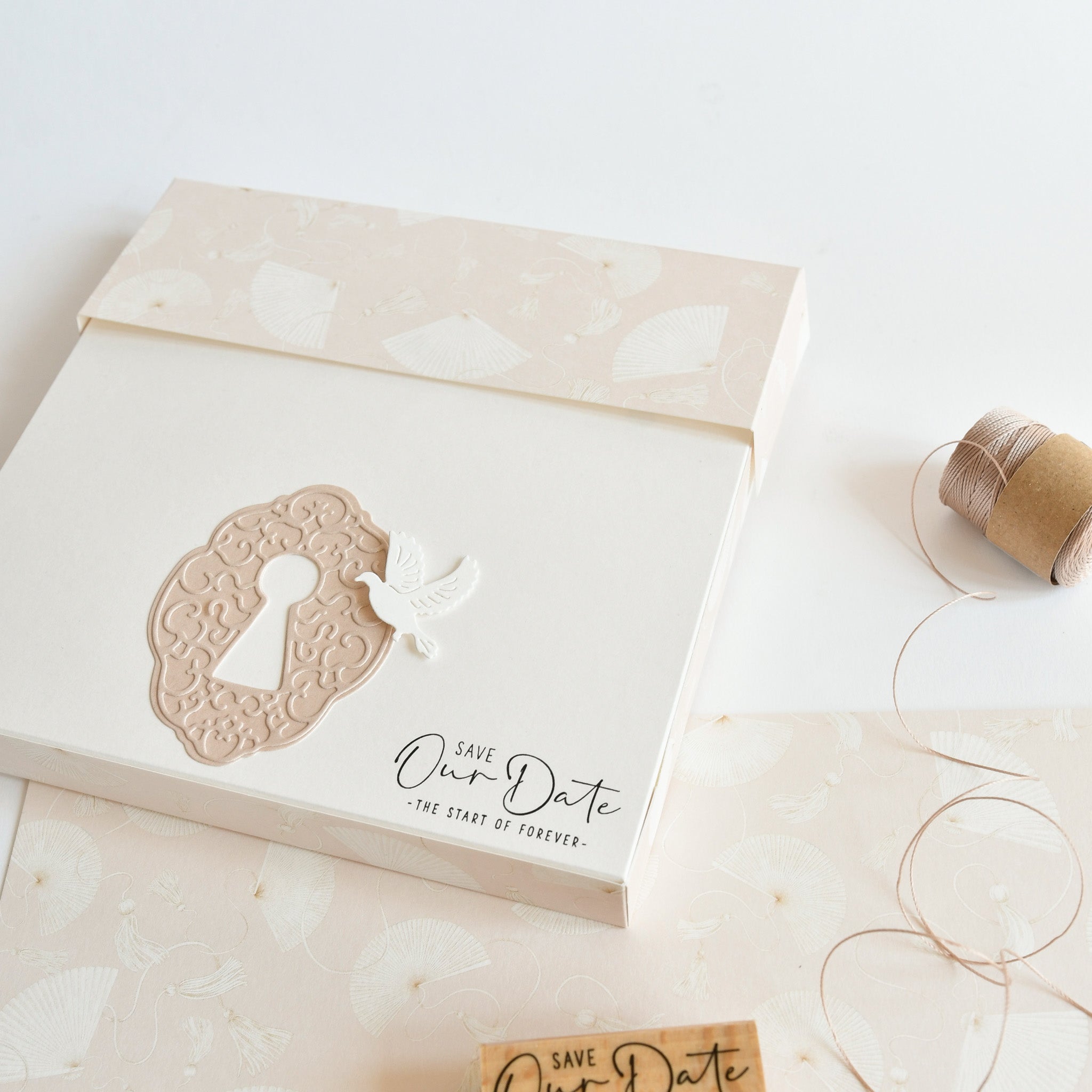 Elegante "Save Our Date"-Hochzeitseinladung von Alexandra Renke mit einem Schlüsselloch- und Taubenmotiv aus hochwertigem Designpapier, das mit rustikalem Garn und gemustertem Papier gestaltet wurde. Ideal für einzigartige Hochzeitspapiere oder kreative Buchbindungsprojekte.