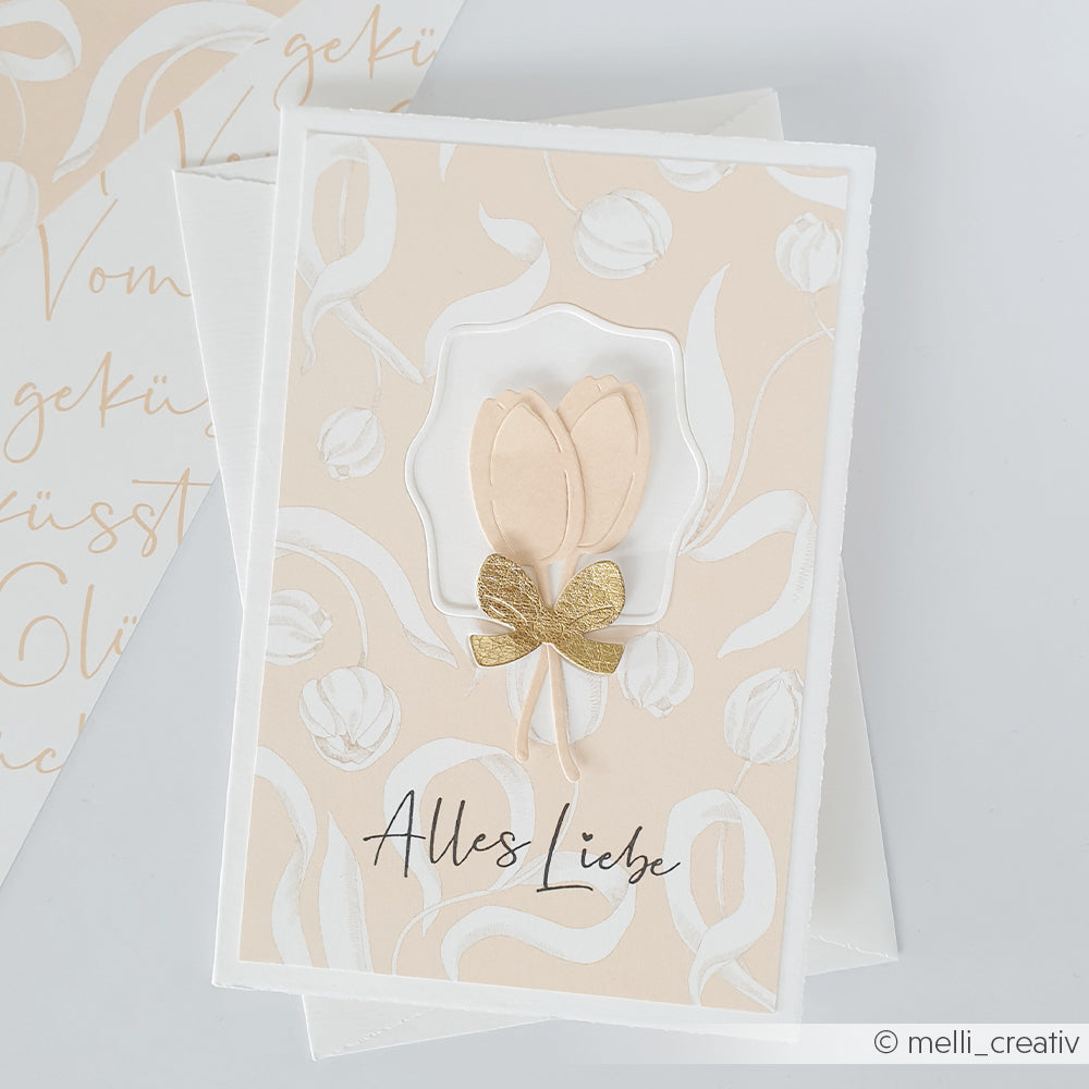 Grußkarte von Alexandra Renke auf feinem Designpapier, mit zwei beigen Tulpen, einer goldenen Schleife und "Alles Liebe" in eleganter Schrift - eine charmante Variante für Grußkartenliebhaber.