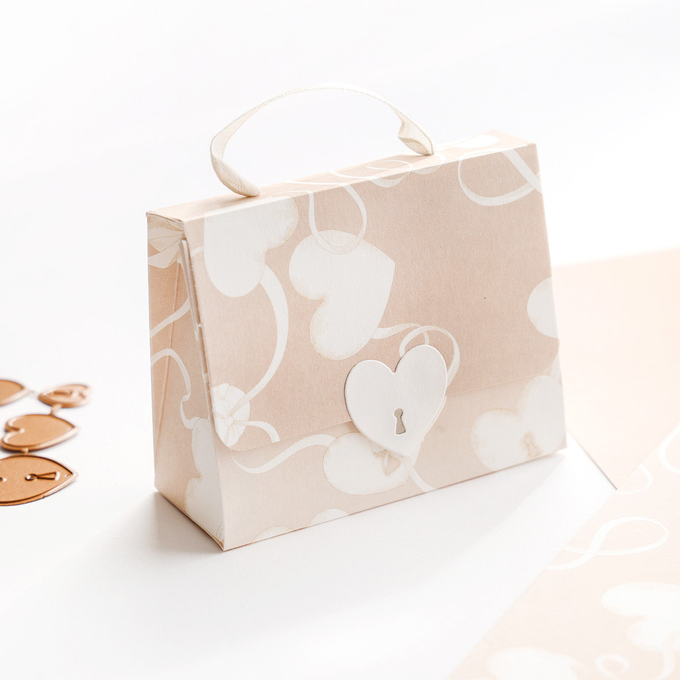 Kleine Geschenkbox mit Herzmotiv von Alexandra Renke's Designpapier, mit Henkel und herzförmigem Verschluss - ideal für Papierprojekte. Ausgestellt auf einer weißen Fläche mit zarten rosa Herzen.