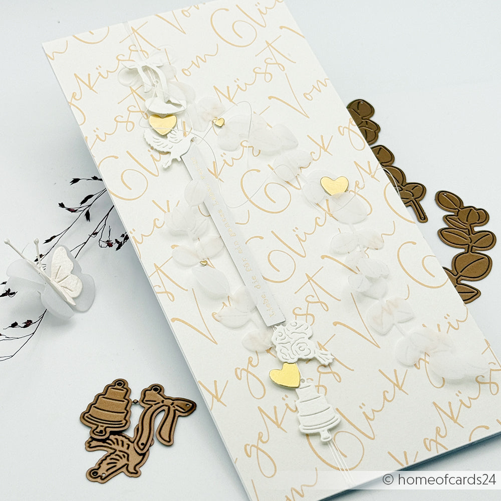 Elegante Hochzeitskarte von Alexandra Renke mit weißen Blumen, goldenen Herzen und zarten Verzierungen auf einem handgeschriebenen Schrifthintergrund - ideal für Papierprojekte oder Buchbinderei-Kreationen.
