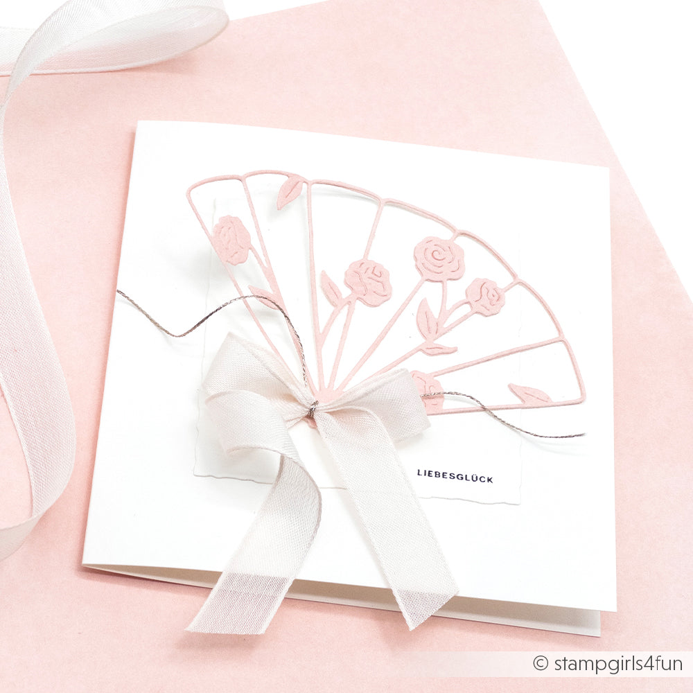 Quadratische weiße Karte mit rosafarbenem Fächer- und Rosendesign, gebunden mit einer weißen Schleife auf rosafarbenem Hintergrund - perfekt für Papierprojekte oder Buchbinderei. Gefertigt aus hochwertigem Designpapier von Alexandra Renke.