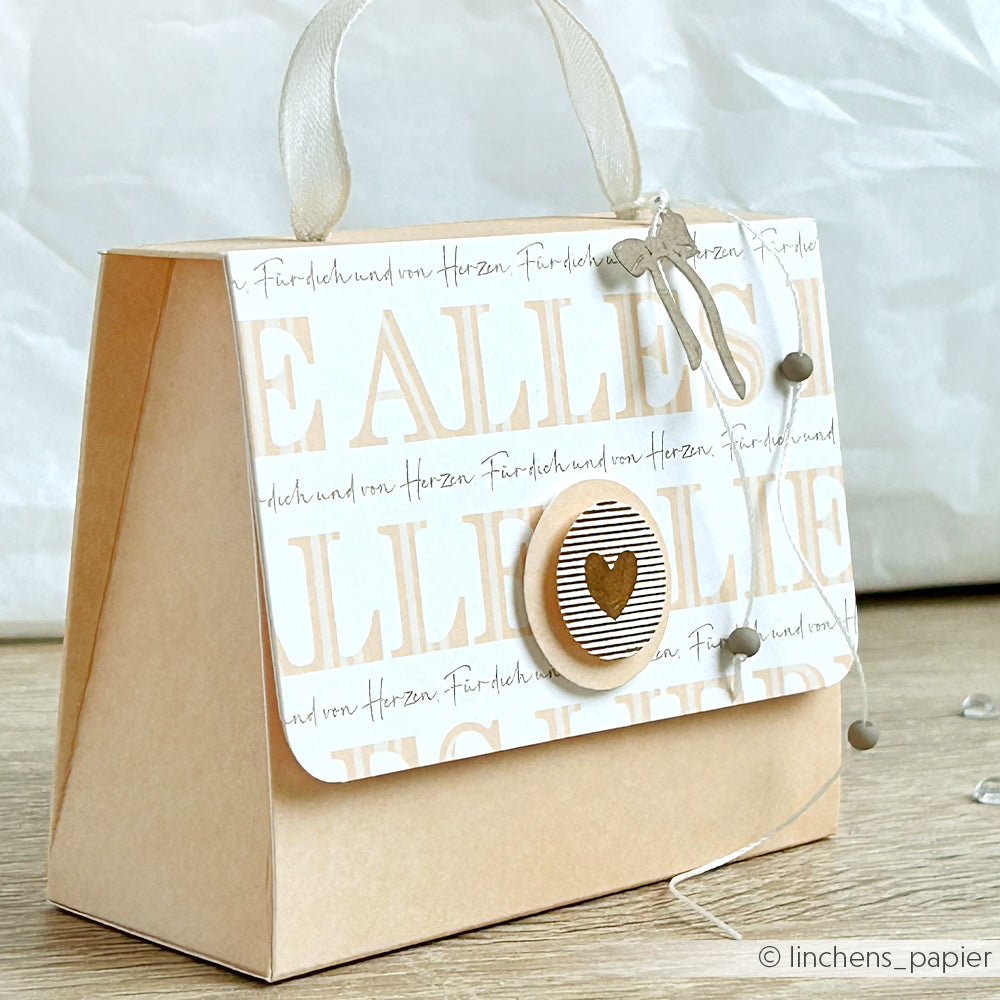 Eine handgefertigte Papiertasche in Form einer Handtasche von Alexandra Renke, mit elegantem Designpapier, einem Herzknopf und einem Bandhenkel - ideal für einzigartige Papierprojekte.