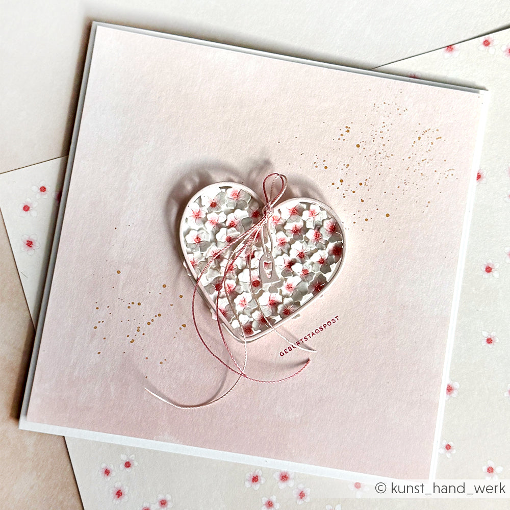 Quadratische Karte von Alexandra Renke mit Blumenherz, rosa Schleife und goldenen Punkten auf pastellfarbenem Hintergrund - ideal für Papierprojekte oder in Kombination mit Designpapier Kirschblüten aus Ihrer Lieblingsbuchbinderei.