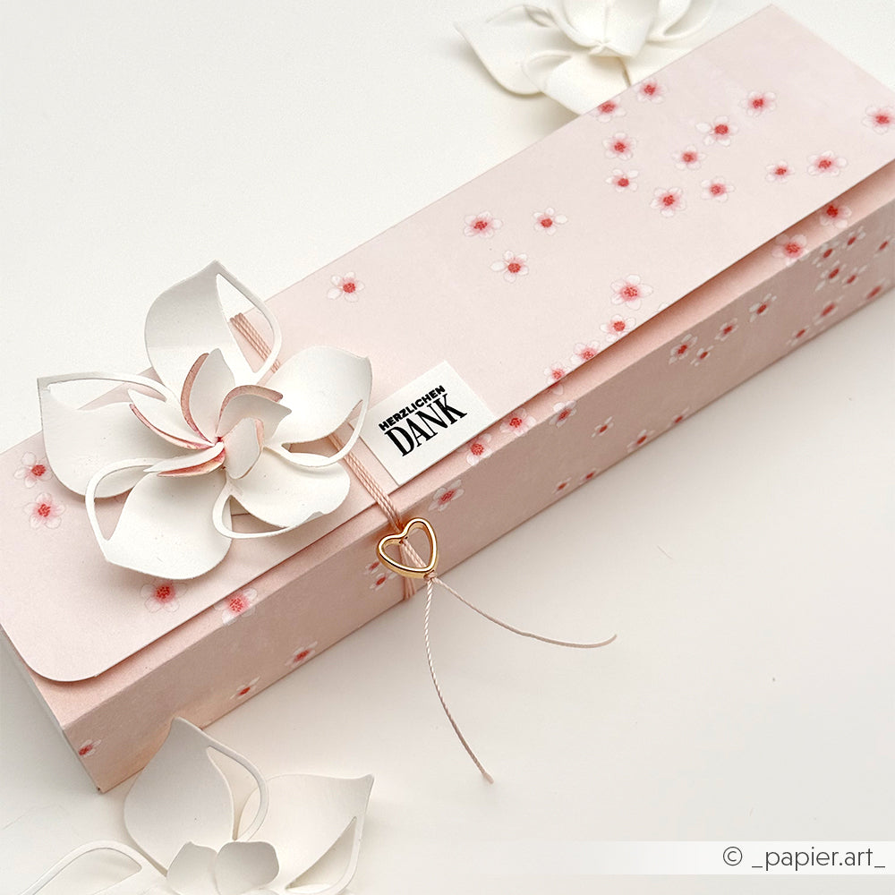 Rechteckige rosafarbene Blumenbox von Alexandra Renke aus Designpapier, verziert mit weißen Kirschblüten, einem DANK-Schild und einem goldenen Herzanhänger - ideal für Ihre Papierprojekte.